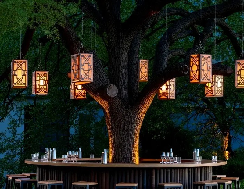 Nighttime Outdoor Bar Setup with Copper Lanterns Under an Oak Tree