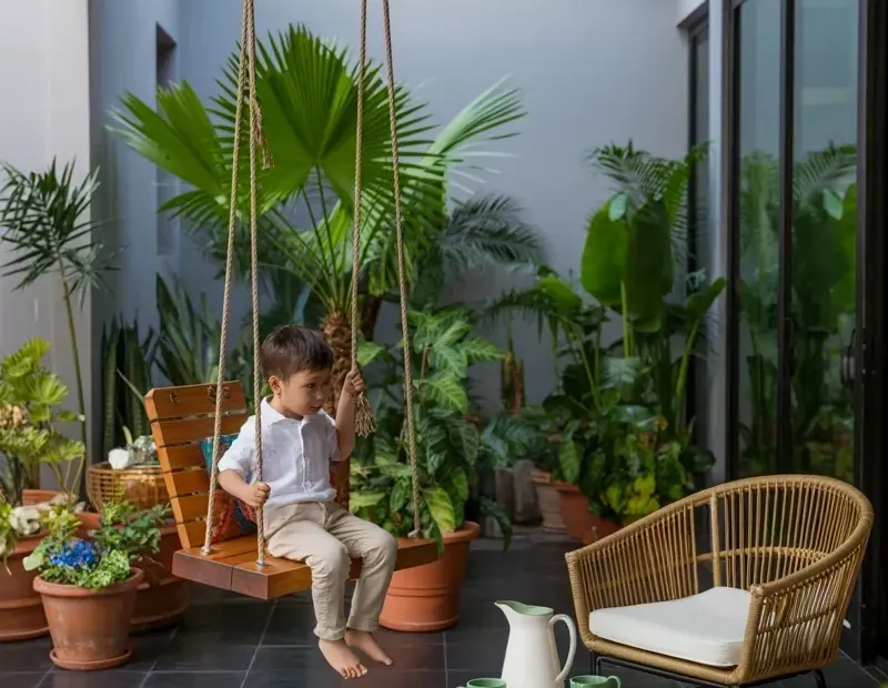 Indoor Outdoor Living Space with Wooden Hanging Swing Chair and Palm Plants